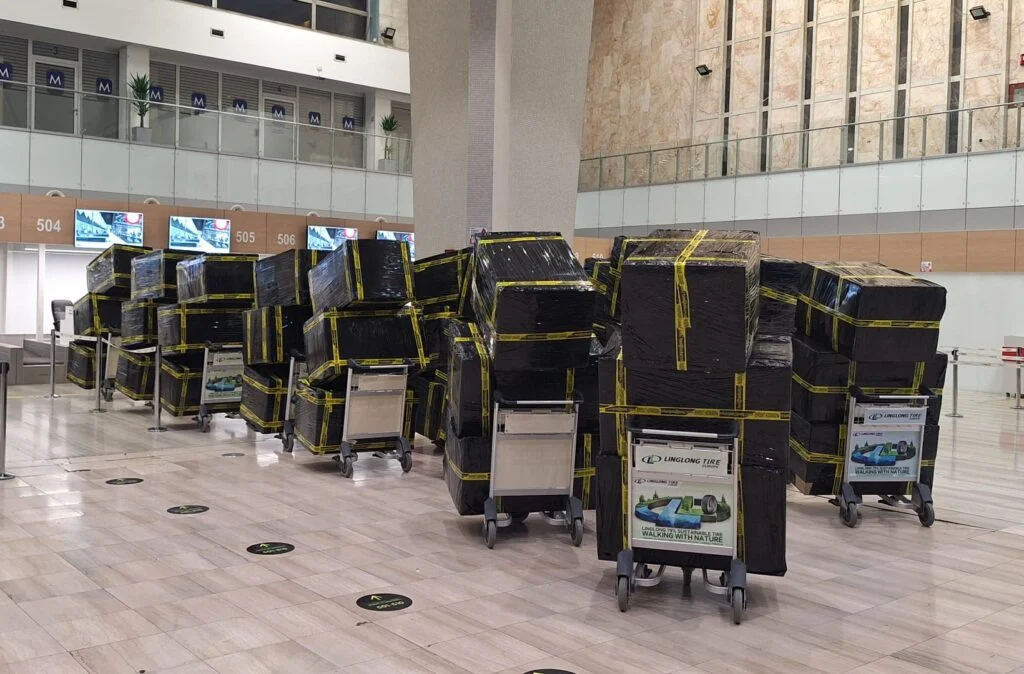 Large shipment of wrapped packages on airport baggage carts